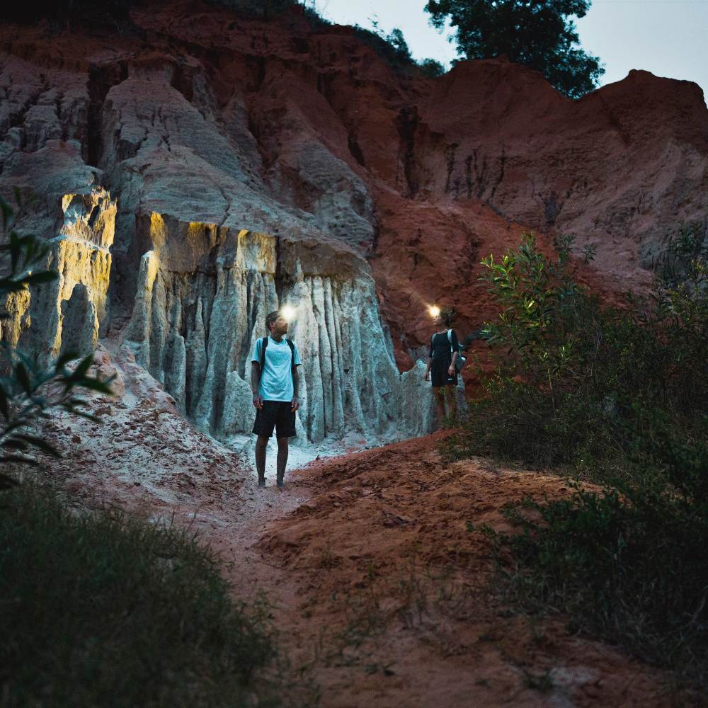 Two people stood in in a rocky scenery at dusk wearing Ledlenser HF4R headtorches