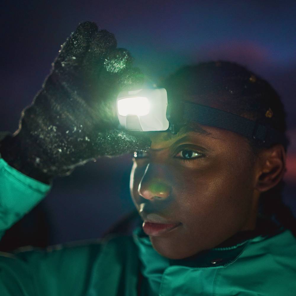 Woman turning Ledlenser HF6R headtorch on while wearing snowy gloves