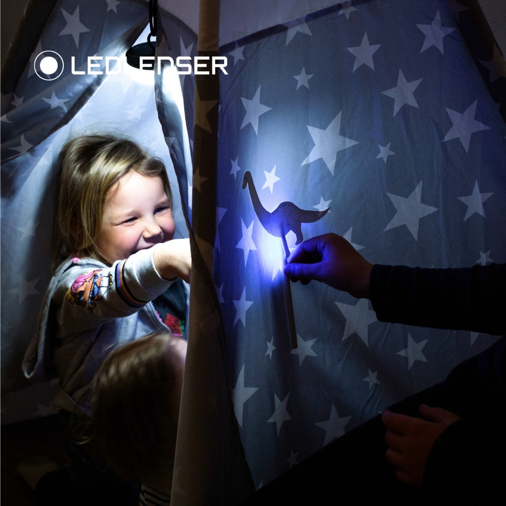 Child playing with a shadow puppet on a star-patterned screen, with Ledlenser branding.
