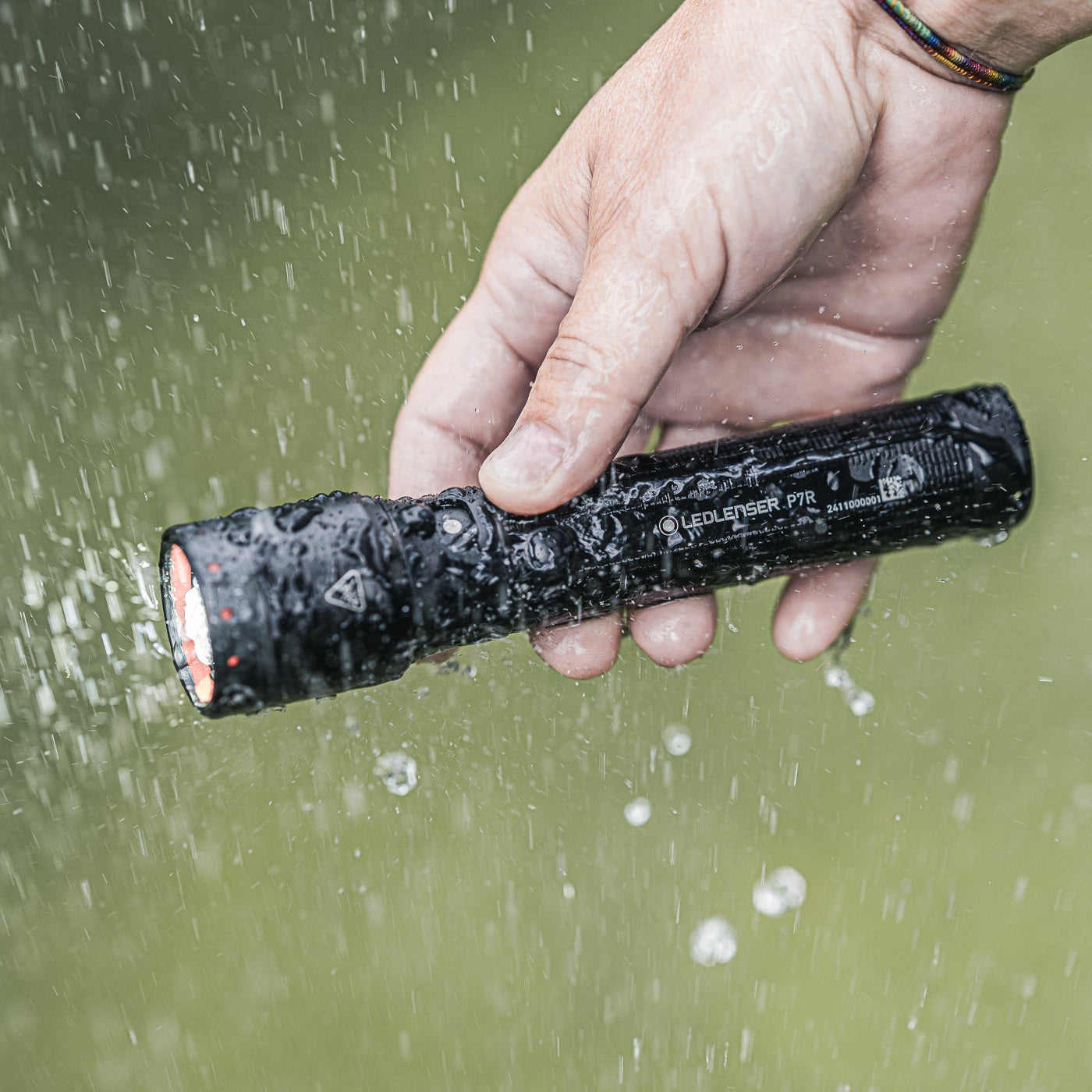 Hand holding a P7R torch under water with droplets visible