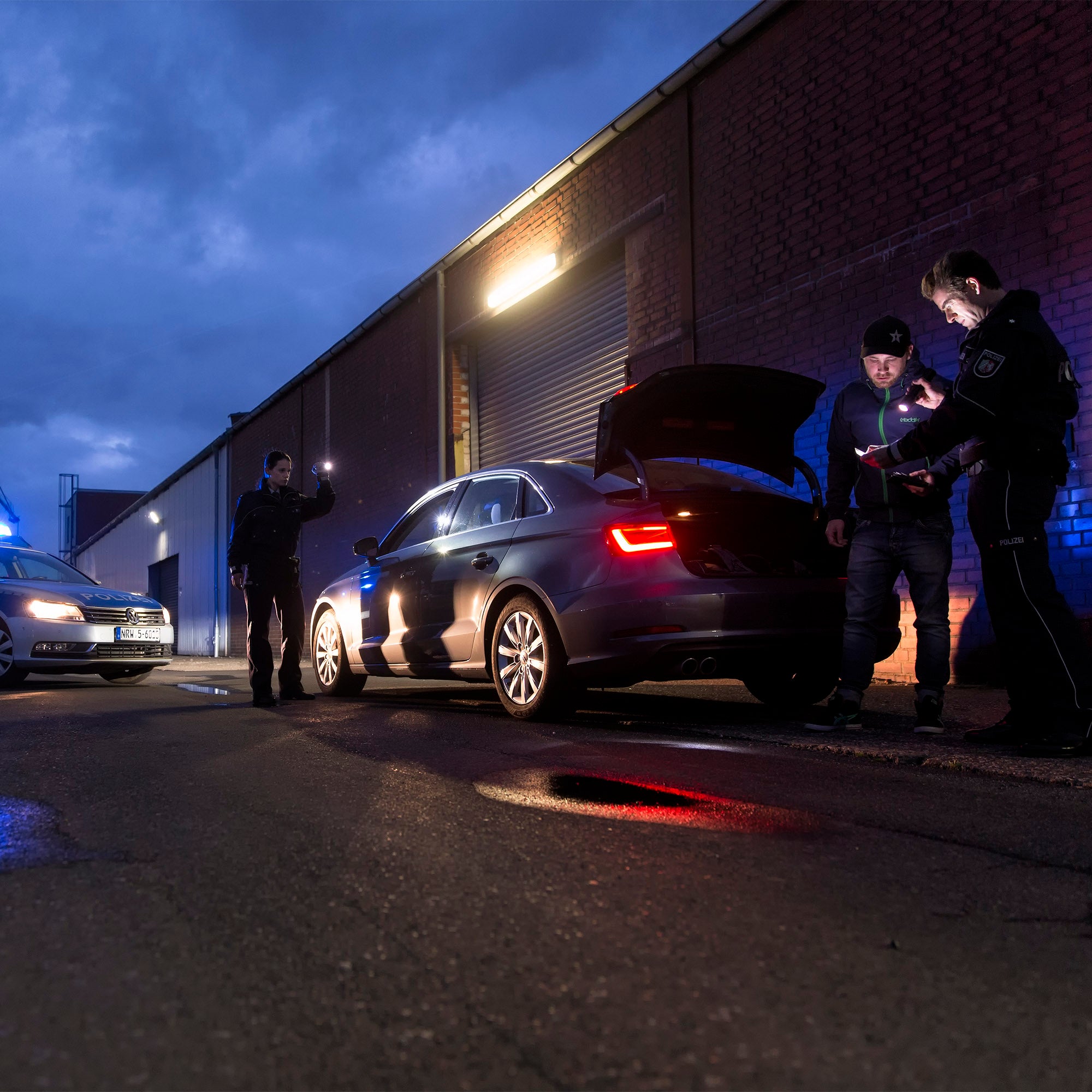 Police checking documents and the exterior of a vehicle outside a warehouse using LEDLENSER T2